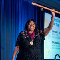 2027-2028 NOMA President Saundra Little raises the staff of office at the 2026 Awards Banquet